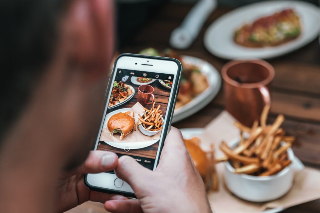 mann fotografiert burger mit seinem smartphone